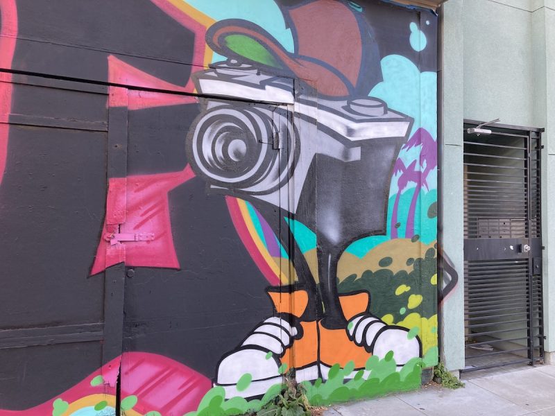 mural of a camera with legs and sneakers