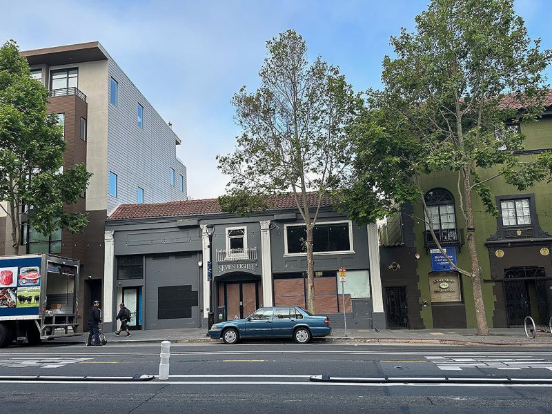 The photo of the front of the building with its windows papered over and a delivery truck to the left.