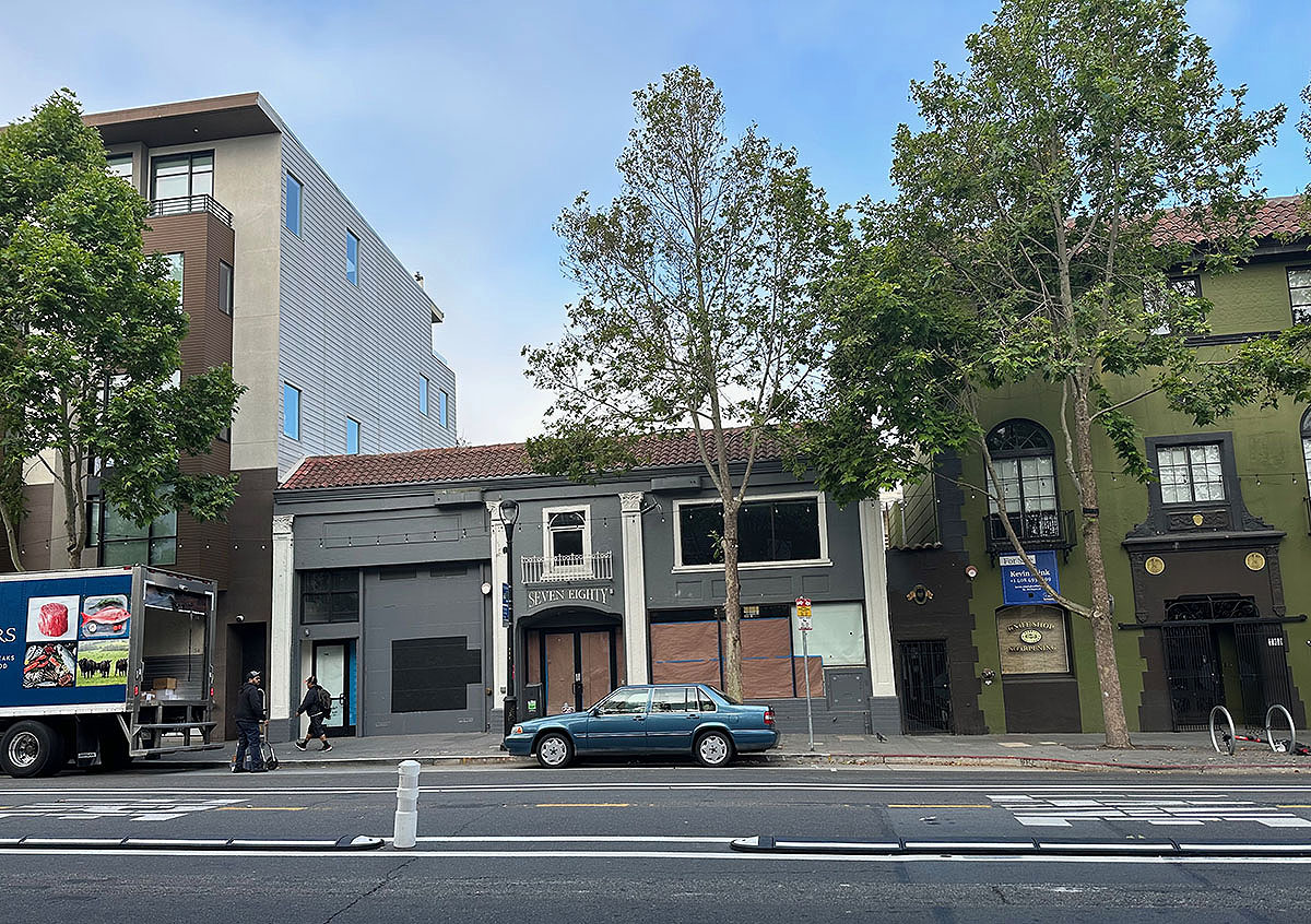The photo of the front of the building with its windows papered over and a delivery truck to the left.