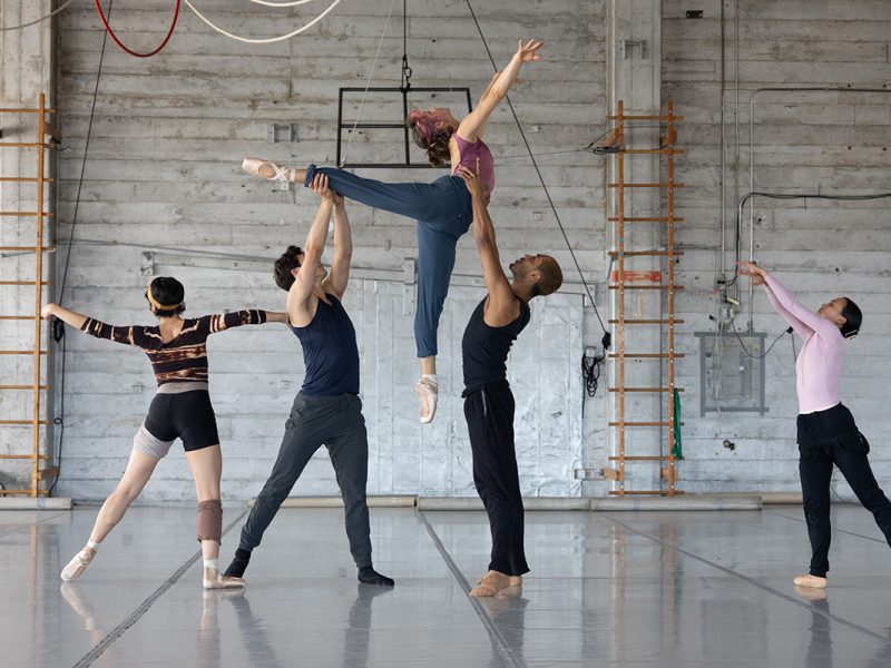 Five dancers with one aloft. All in sweats or dance gear. Amy Seiwert (center and aloft).