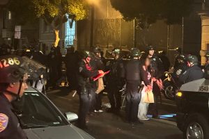 A young person with face blotted out being arrested.