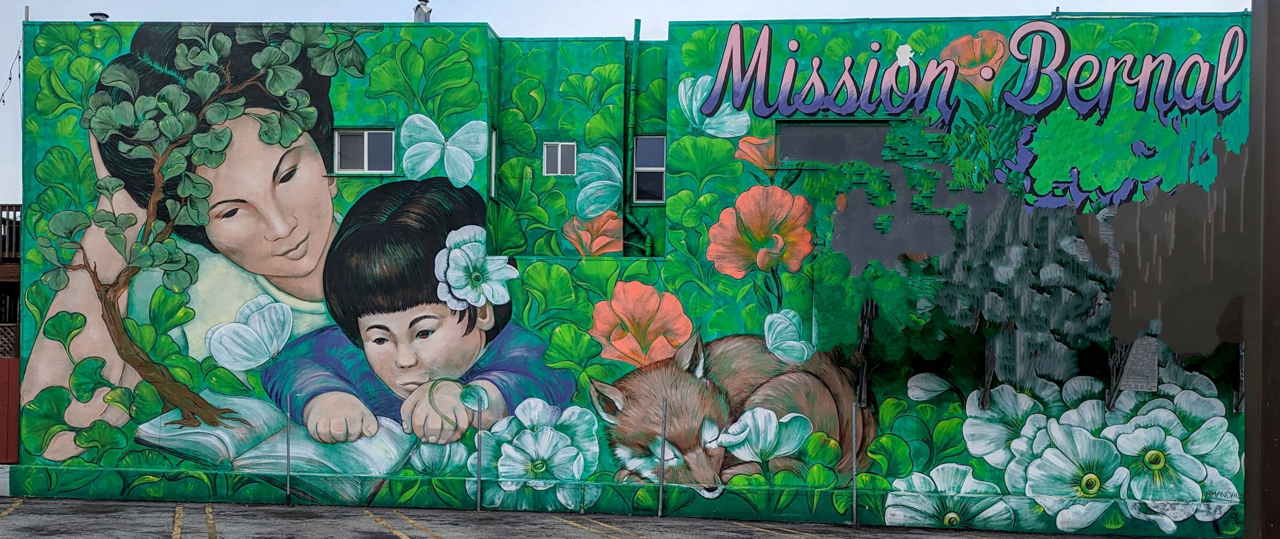 A mural of a mother looking over the shoulder of a child reading with a dog nearby, in green and some red. Lots of plants.
