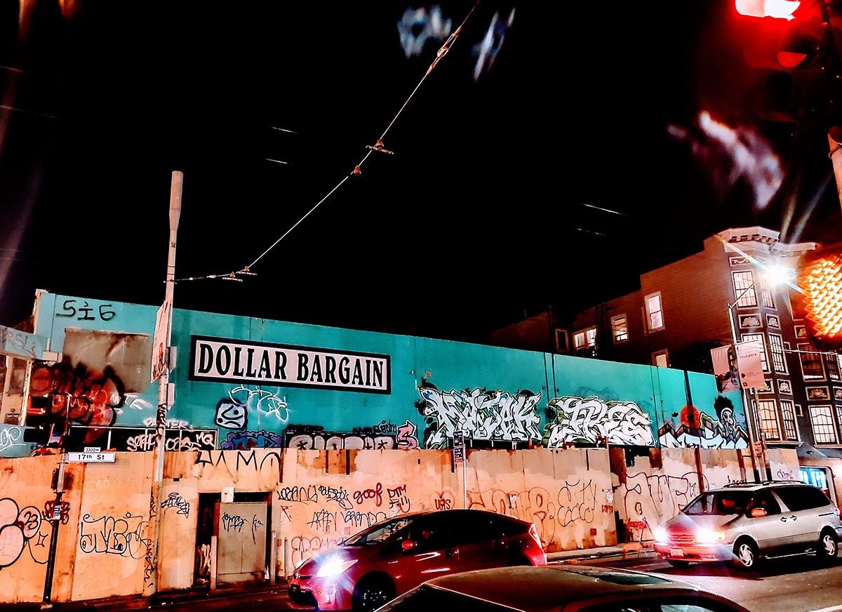 A store painted blue/green with boards in front of it. The scene is at night.