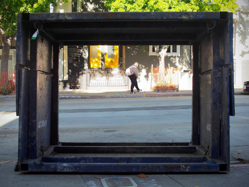 A frame sitting on the sidewalk and across the street, we can see a child playing