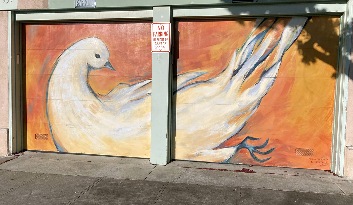 A dove painted on a garage door in white with an orange background.