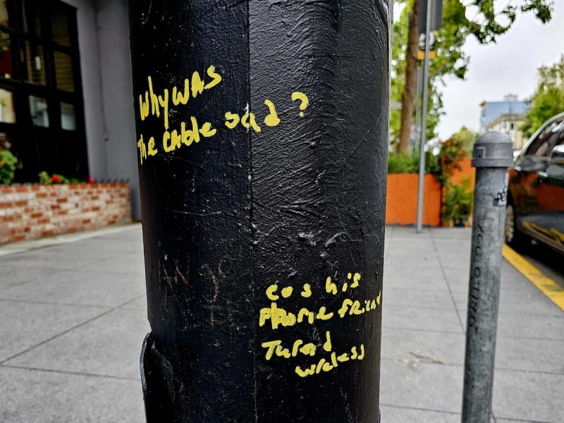 yellow marker graffiti on black pole