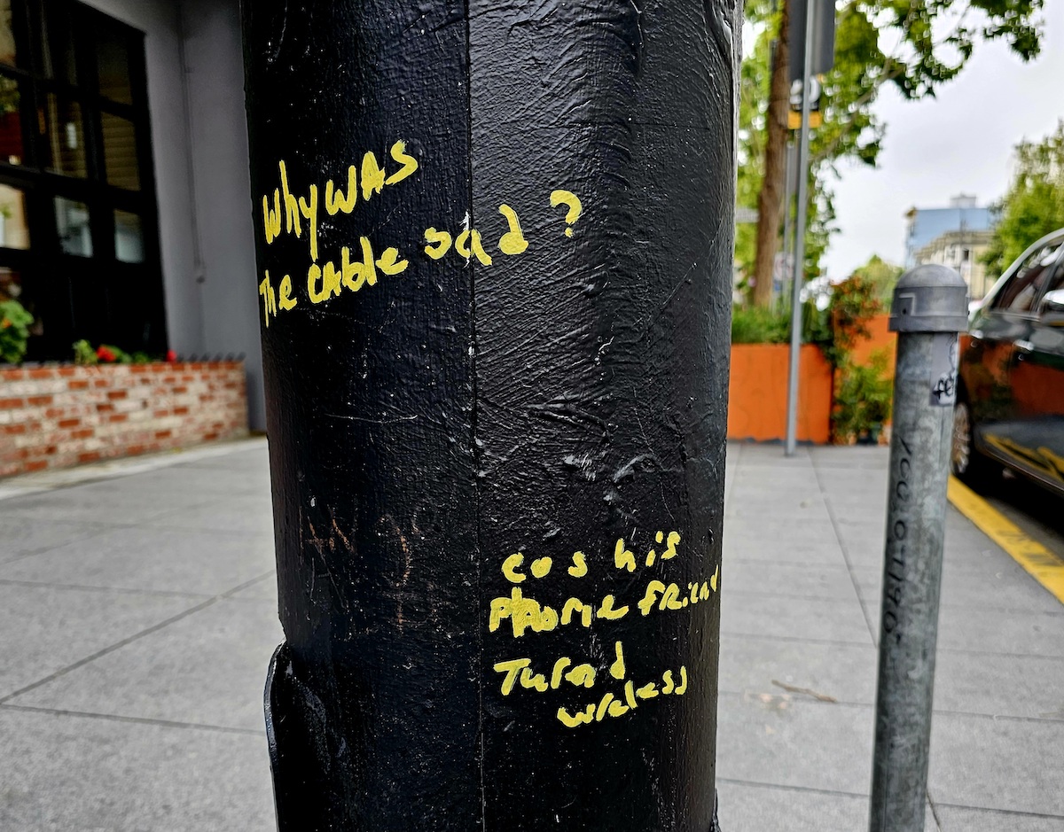 yellow marker graffiti on black pole