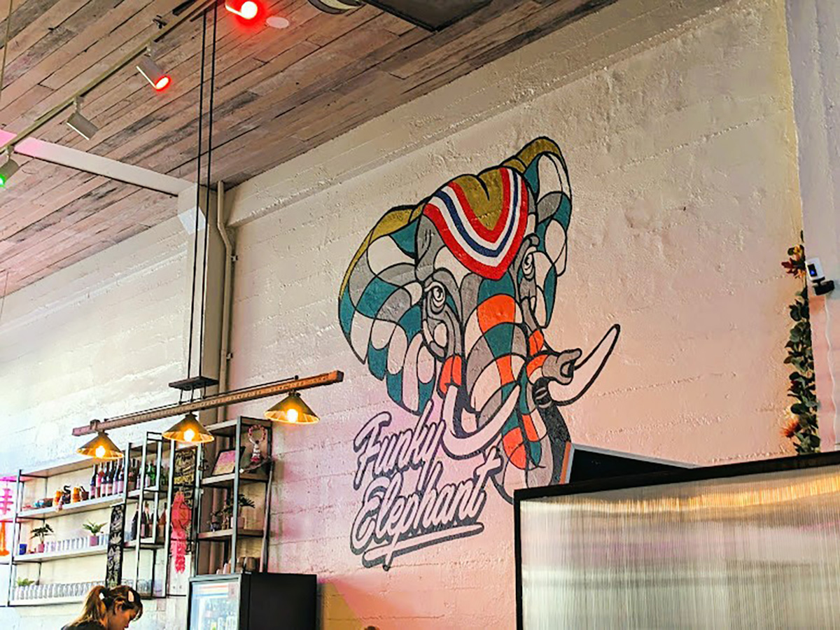 A wall with an elephant head painted in green and red checks, lights .