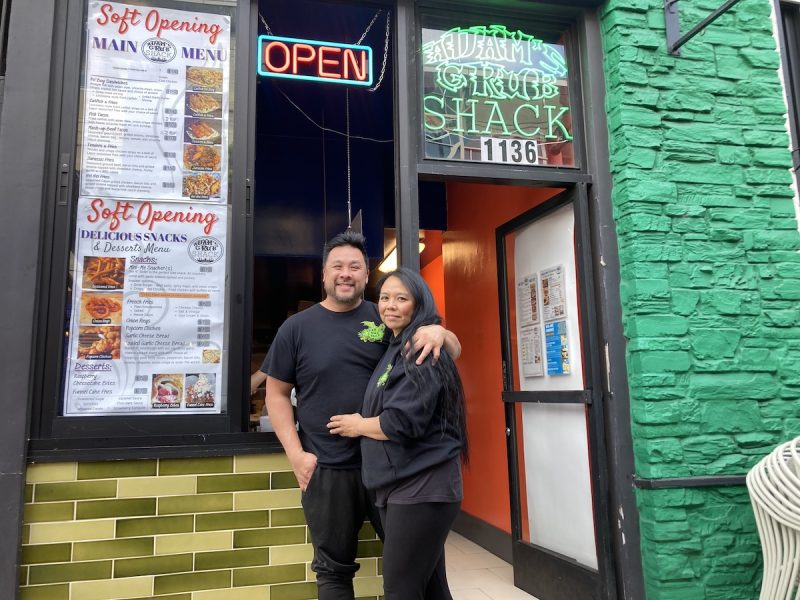 A man and a woman stand in front of a restaurant