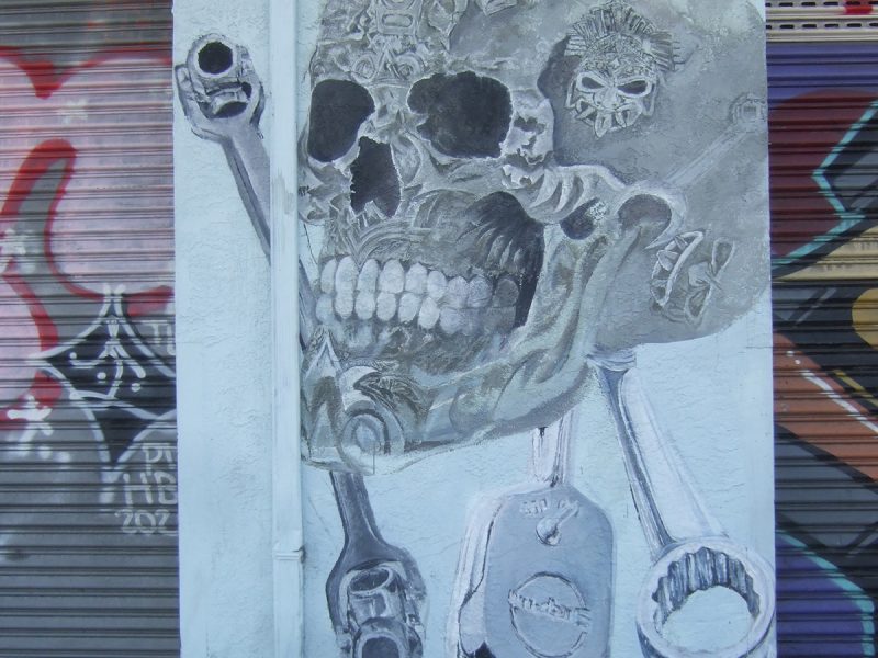 A black and white skull painted on a wall with some mechanical tools