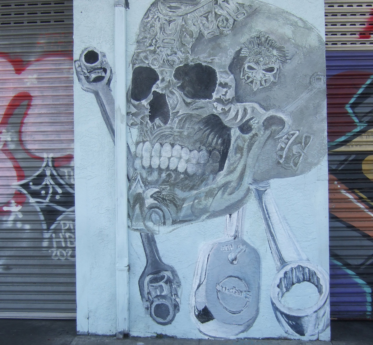 A black and white skull painted on a wall with some mechanical tools