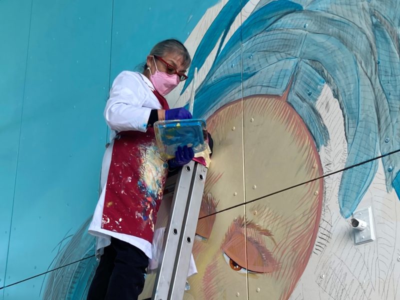 A muralist painting a wall.