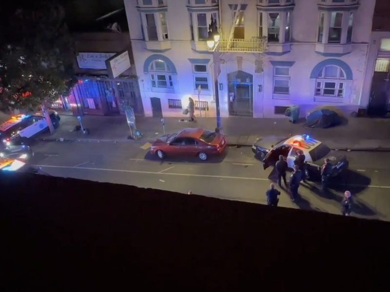 Photo shows Everett standing on the pavement in the spotlight, with police officers standing around, surrounding him.