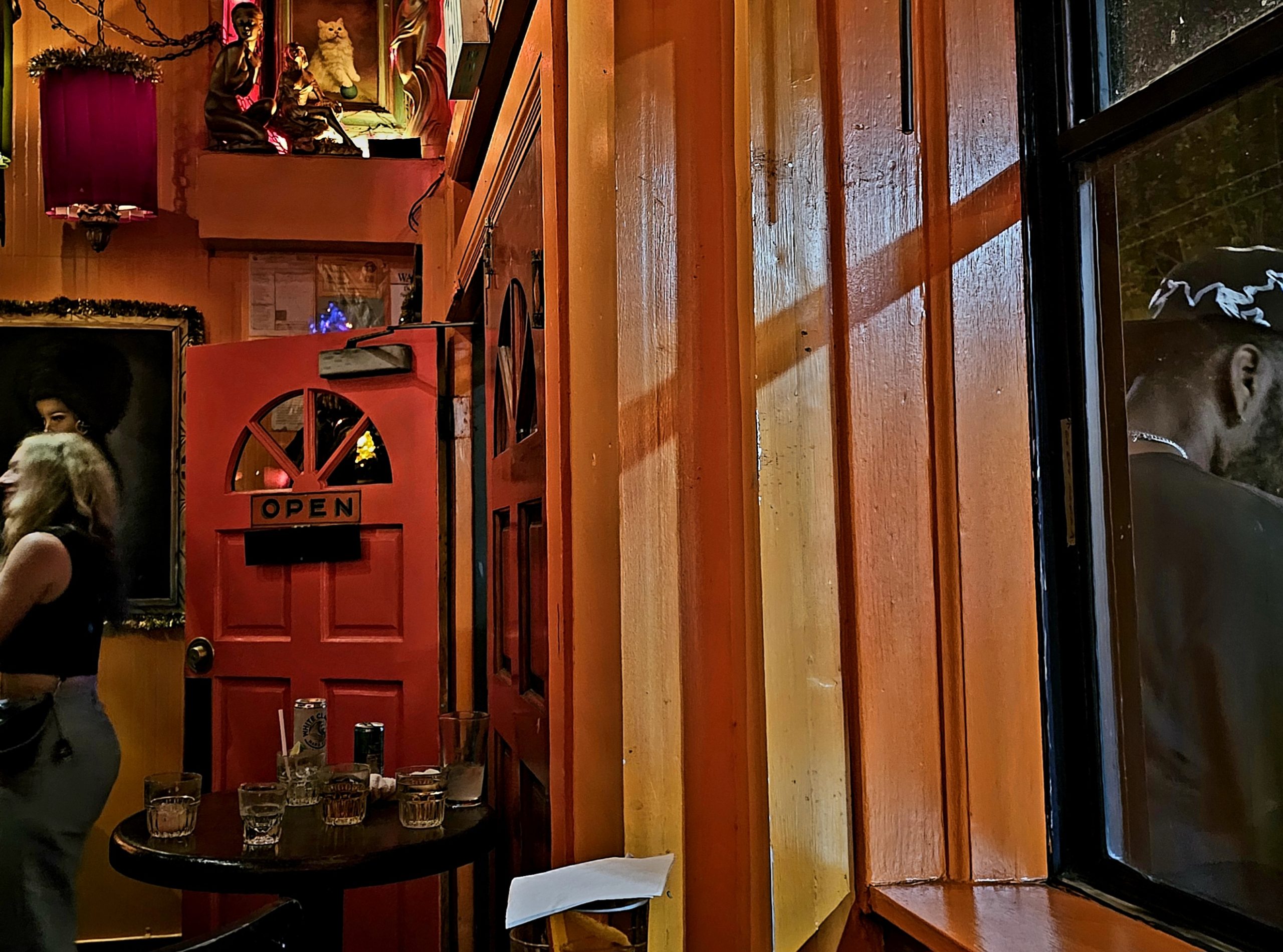 A sign that says "open" on a red door to a bar.