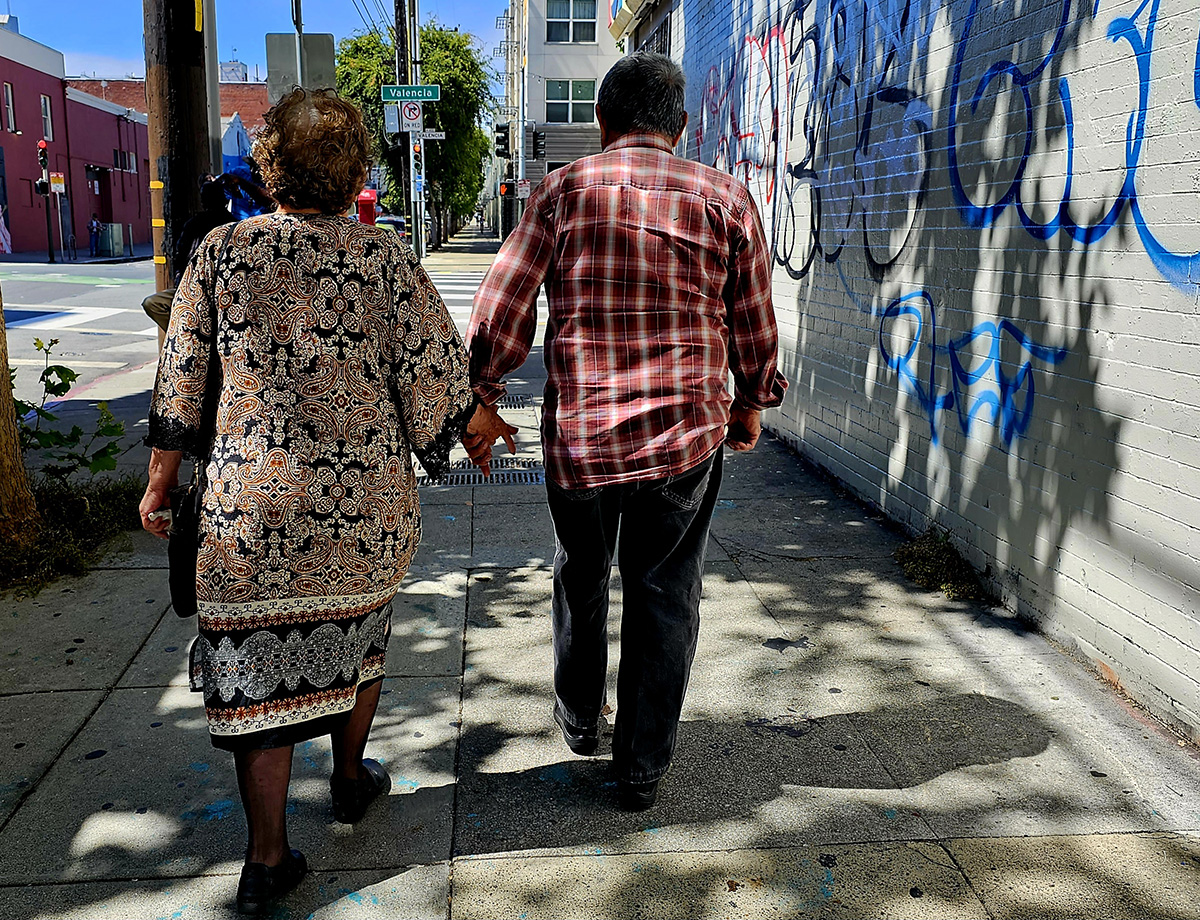 A middle aged couple from the back holding hands.