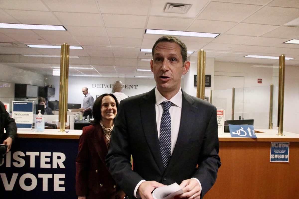Daniel Lurie pulling papers to run for mayor, with his wife Becca Prowda standing behind him