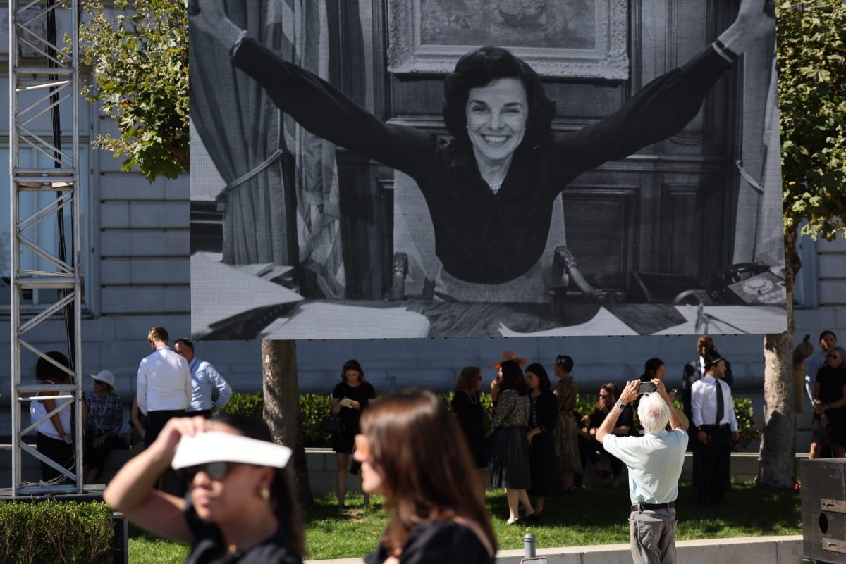 A large photo of Dianne Feinstein on a banner in front of a group of people.