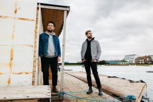 Two men standing on a dock next to a boat.