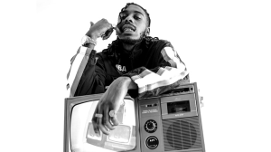 A black and white photo of a man with dreadlocks sitting on top of a television.
