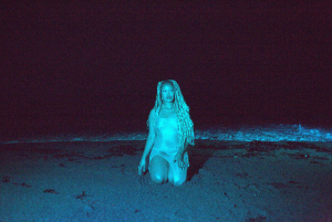 A woman sitting in the sand at night.