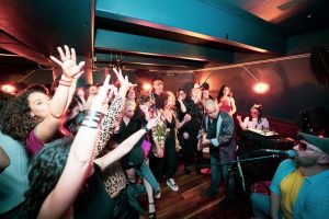 A group of people in a bar with their hands in the air.