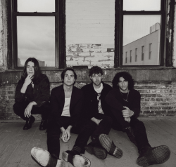 A black and white photo of a group of men sitting in front of a window.