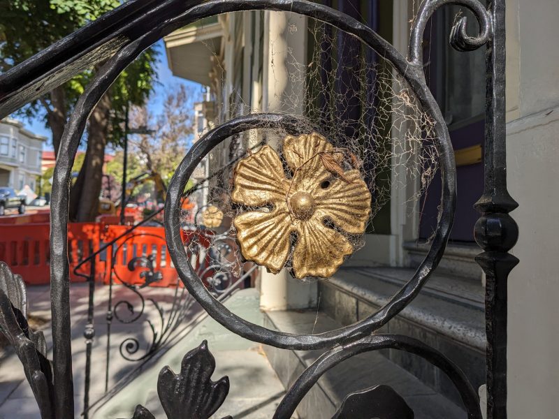 An empty spide web on a black metal stair railing.