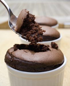 A spoon is being used to take a bite out of a chocolate cake.