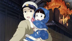 A man and a woman holding a child in front of a fire.