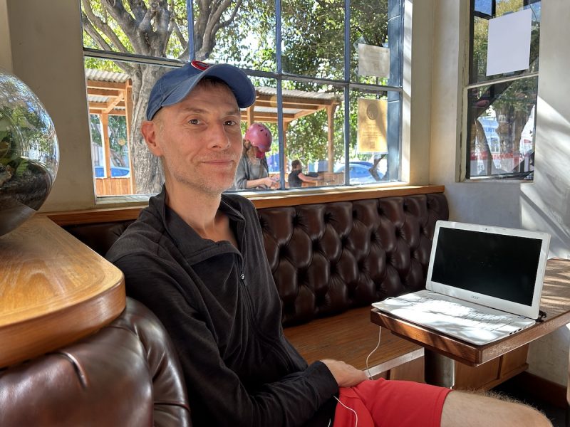 A man sitting at a table with a laptop in front of him.
