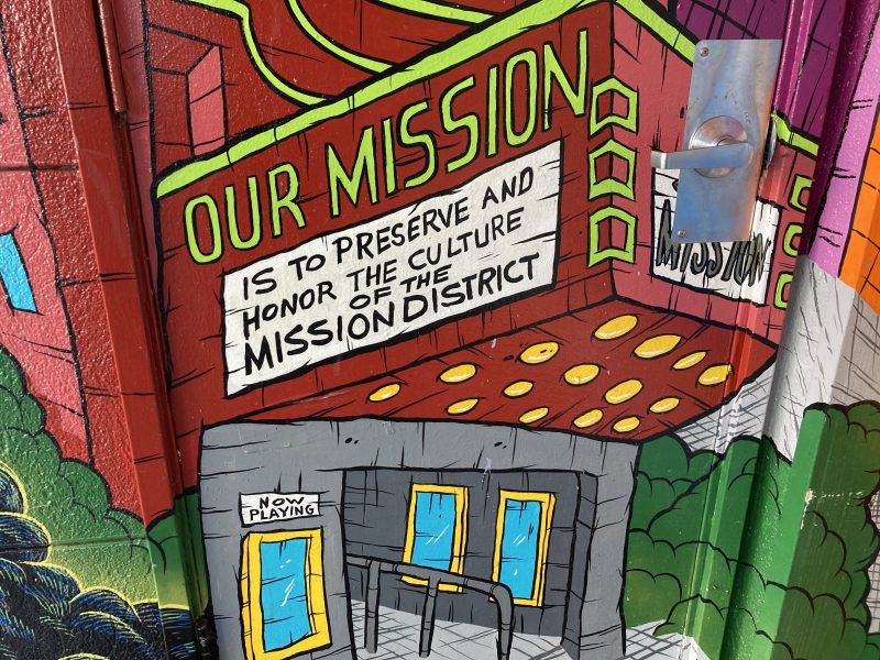 Art on a wall with bright colors that says "Our mission is to preserve and honor the culture of the mission district" in all caps.