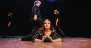 A woman laying on the floor in front of a group of dancers.