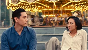 A man and woman sitting in front of a carousel.