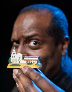 A man holding up a miniature model of a church.