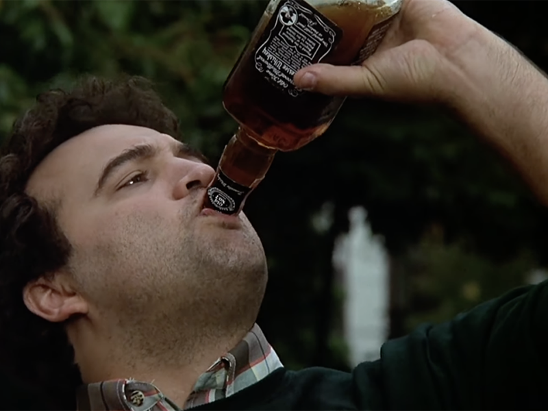 A man drinking from a bottle of whiskey.