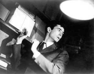 A man in a suit standing in front of a bookcase.