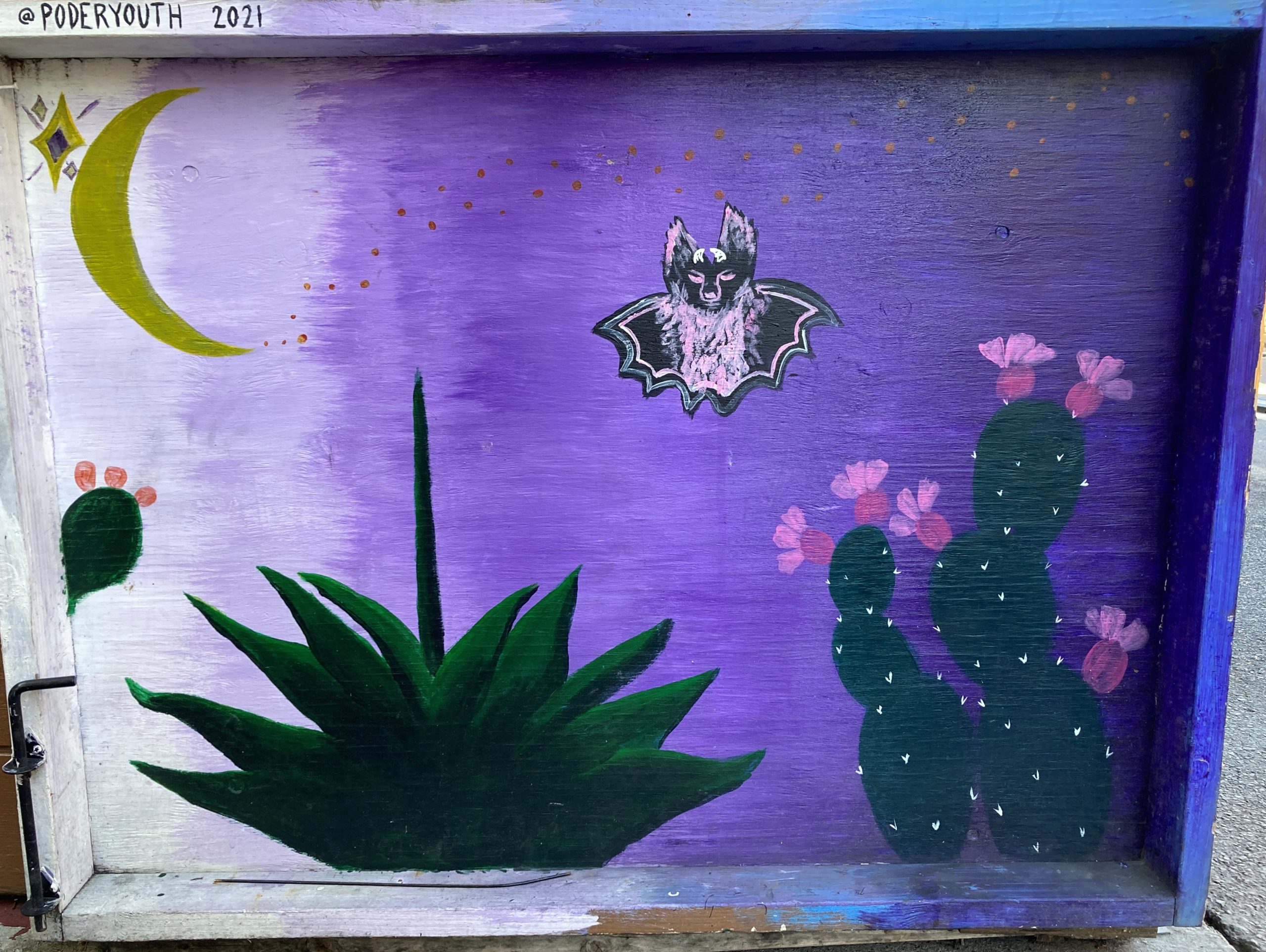 A purple door with a bat and cactus painted on it.