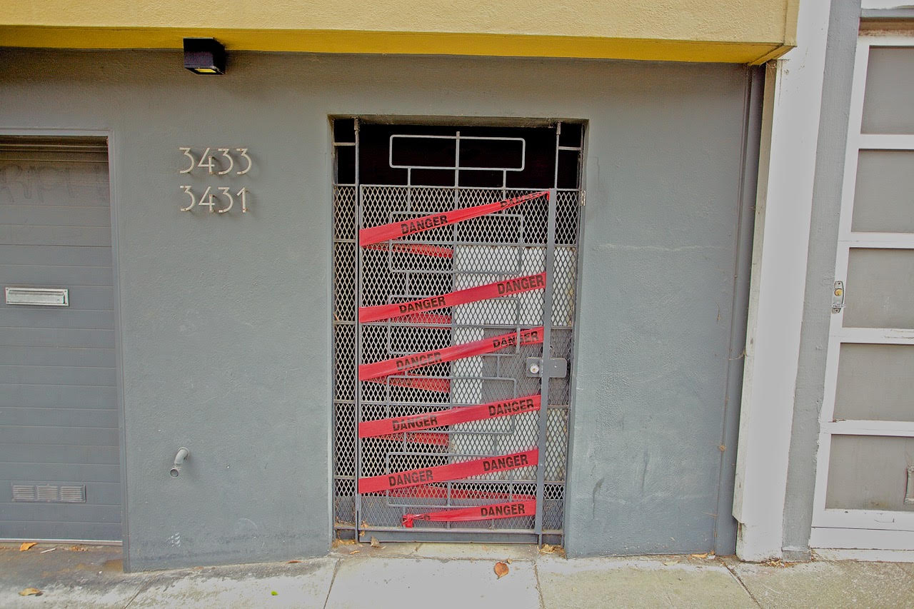 Red tape with the word "danger" written all over it wrapped around a door.