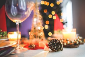 A christmas table setting with candles and pine cones.
