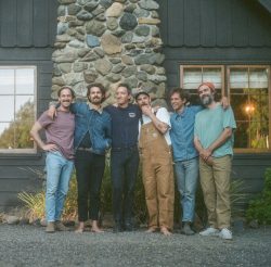 A group of men standing in front of a stone house.