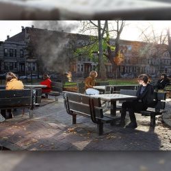 A group of people sitting at tables in a park.
