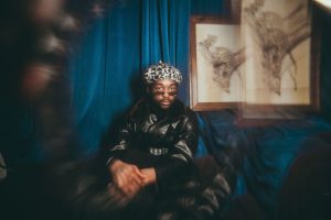 A woman wearing a crown sitting on a chair.