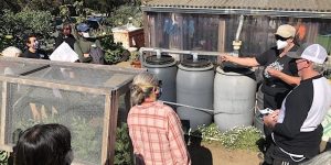 A group of people standing around a group of barrels.