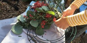 A person is putting berries on a wreath.