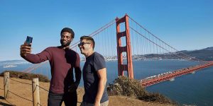 Two men taking a selfie in front of the golden gate bridge.