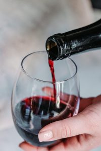 A person pouring red wine into a glass.