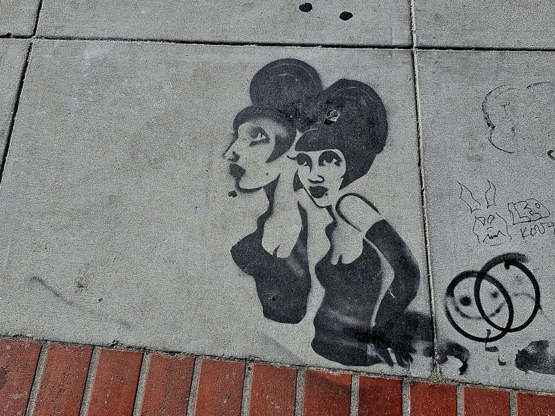 A sidewalk with a stencil of two ladies on it