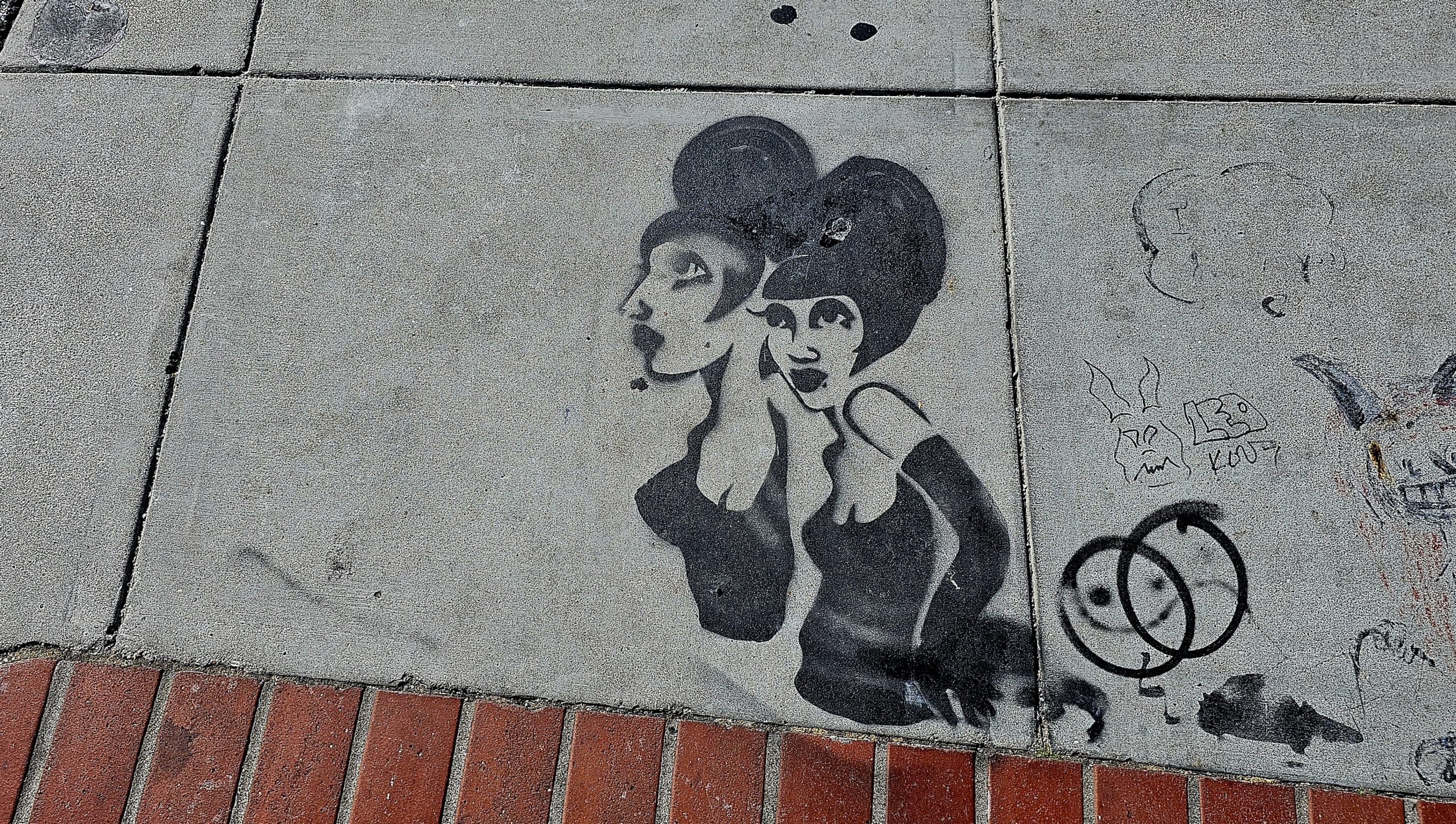 A sidewalk with a stencil of two ladies on it