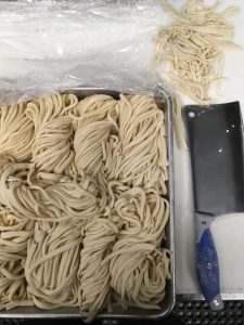 A tray of noodles with a knife next to it.