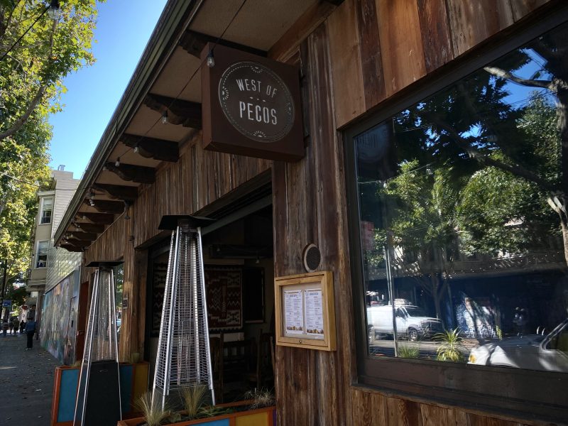 A restaurant with a wooden sign on the side of the building.